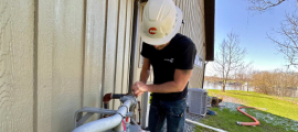 A We Energies natural gas worker works on a natural gas meter near a home on a sunny day.