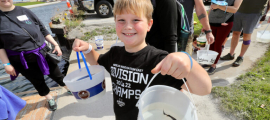 young boy holding buckets smiling