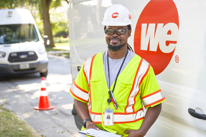 we energies employee squatting down to work on gas facilities for an existing home