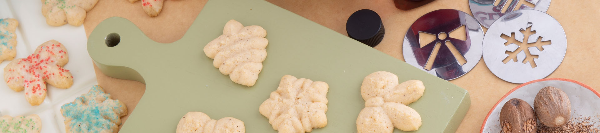 spritz cookies plain and with red and green sprinkles surrounded by cooking ingredients