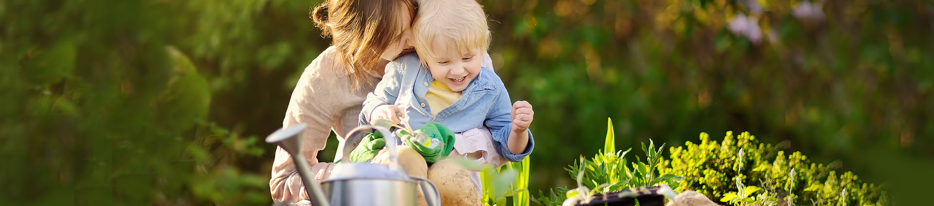 young boy sitting on woman's lap in an embrace gardening and smiling