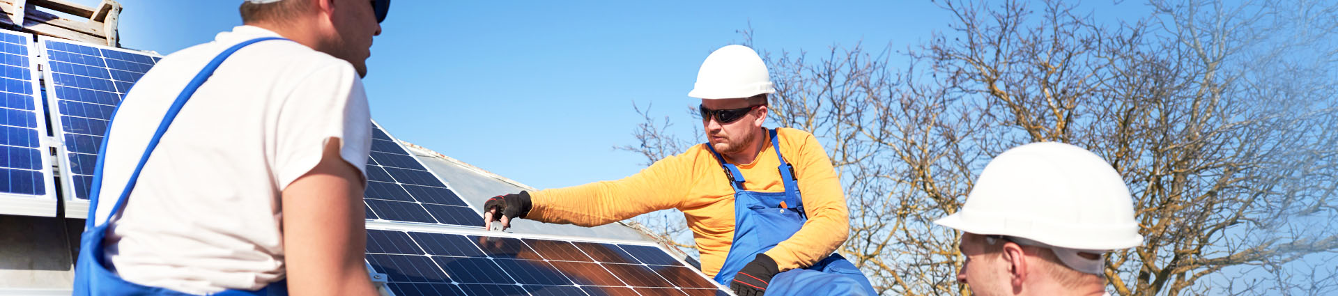 workers on roof top looking at solar panels